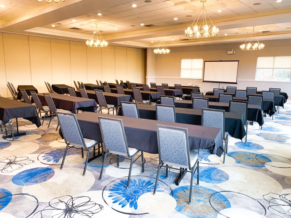 A conference room set up for a meeting with a projector screen and chandeliers